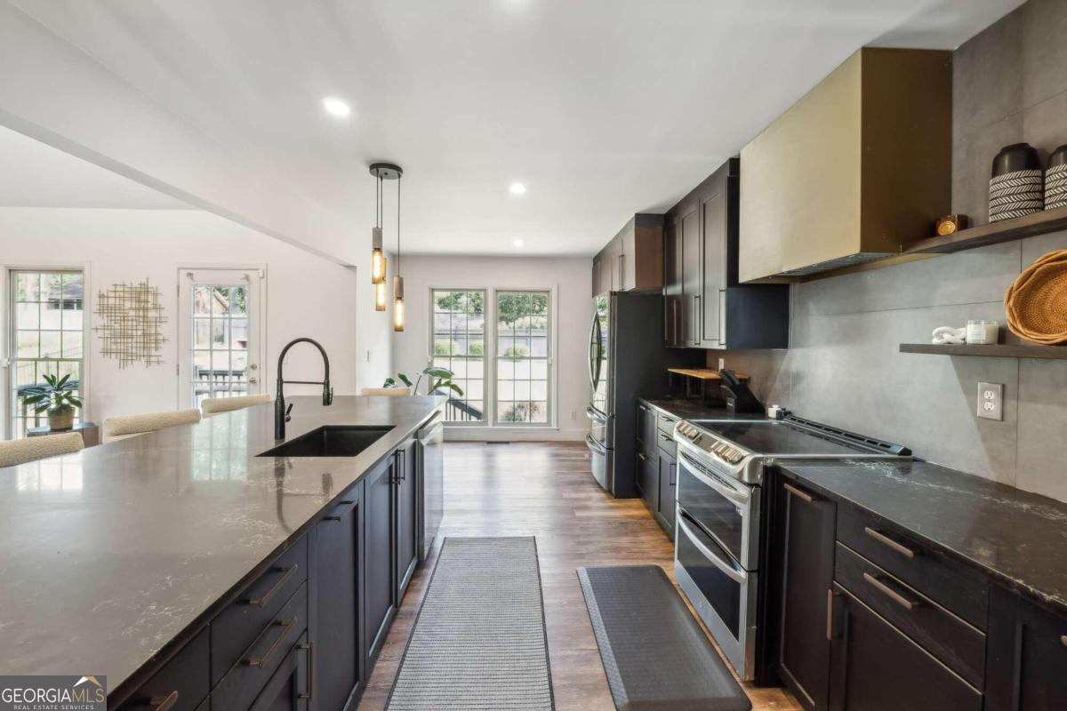 a kitchen with granite countertop a stove a sink dishwasher and cabinets with wooden floor