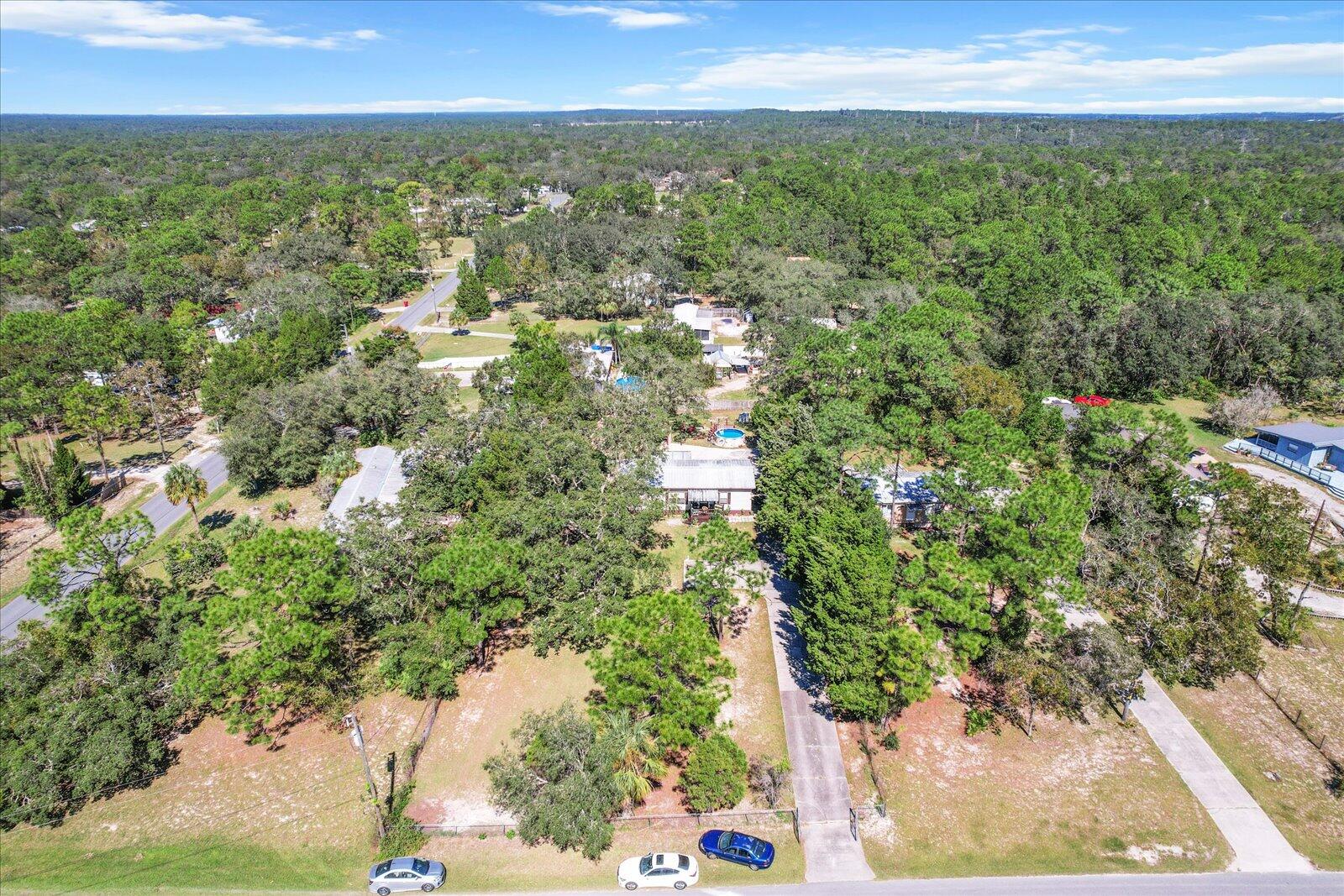 an aerial view of residential houses with outdoor space and trees