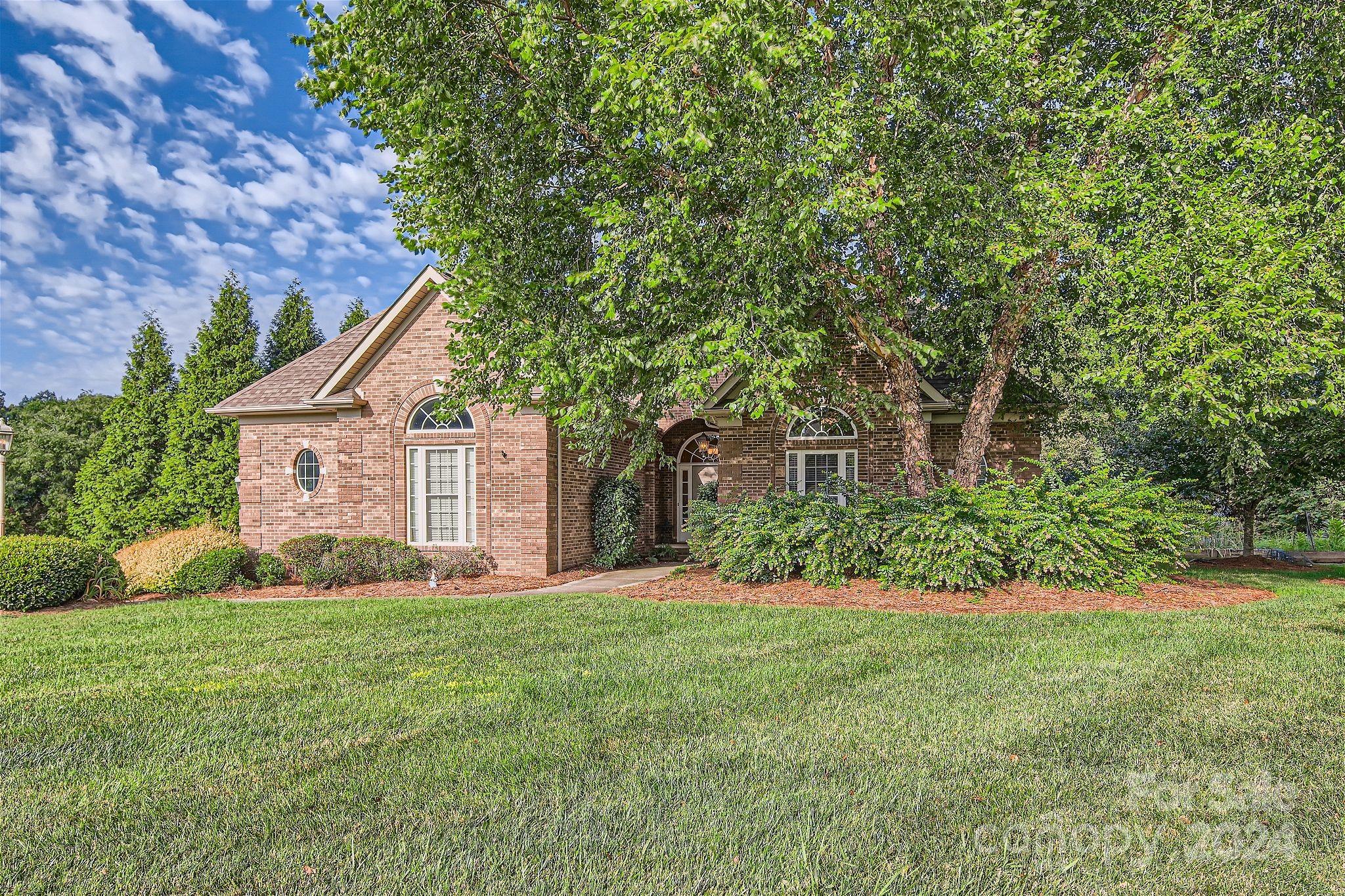 a front view of a house with a yard and trees