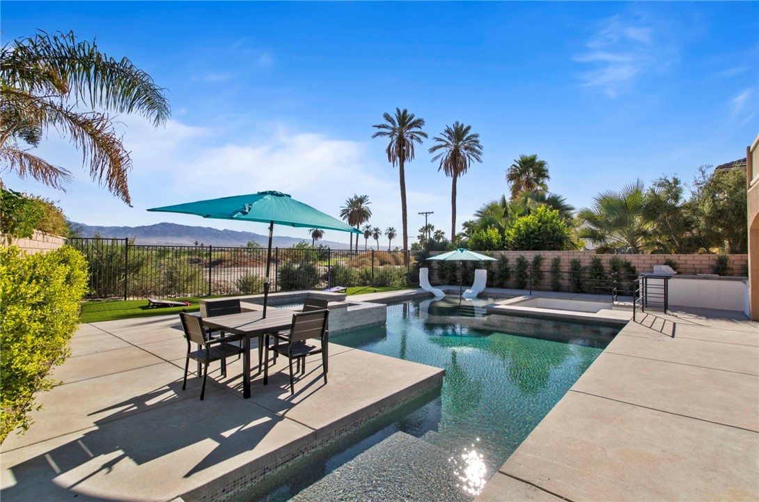 a view of a patio with couches and table and chairs with potted plants and palm trees