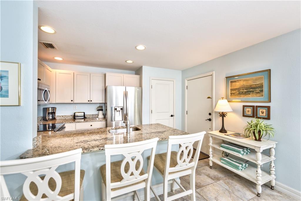 a dining hall with stainless steel appliances kitchen island granite countertop a sink and cabinets