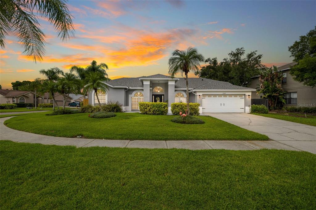 a view of house with a big yard and palm trees