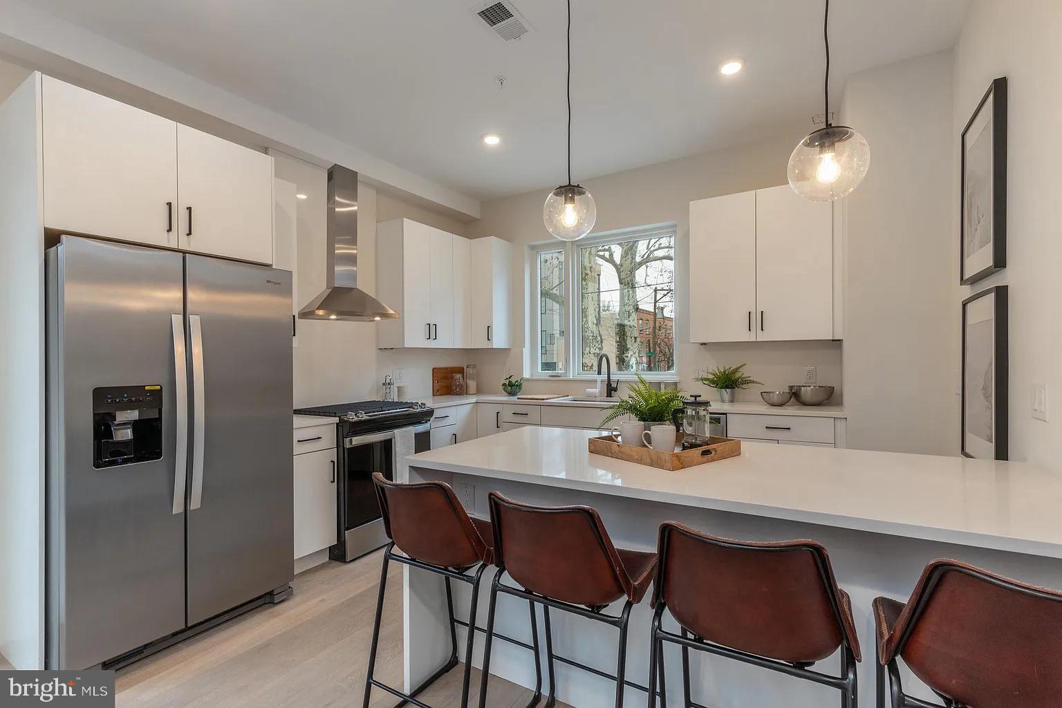 a kitchen with refrigerator a sink and chairs