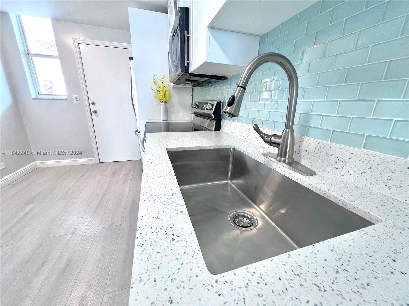 a view of a sink a faucet a washer and dryer in a kitchen