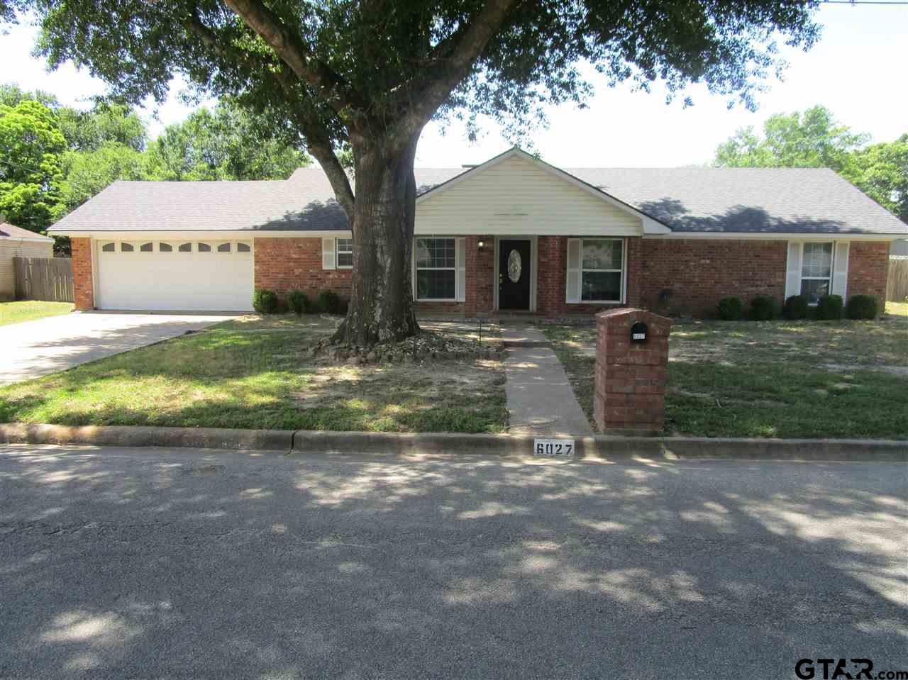 a view of a yard in front of a house with large tree