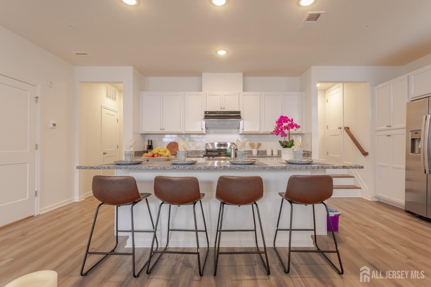 a kitchen with granite countertop a dining table chairs and wooden floor