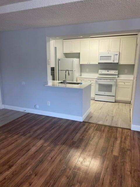 a kitchen with wooden floors and white stainless steel appliances