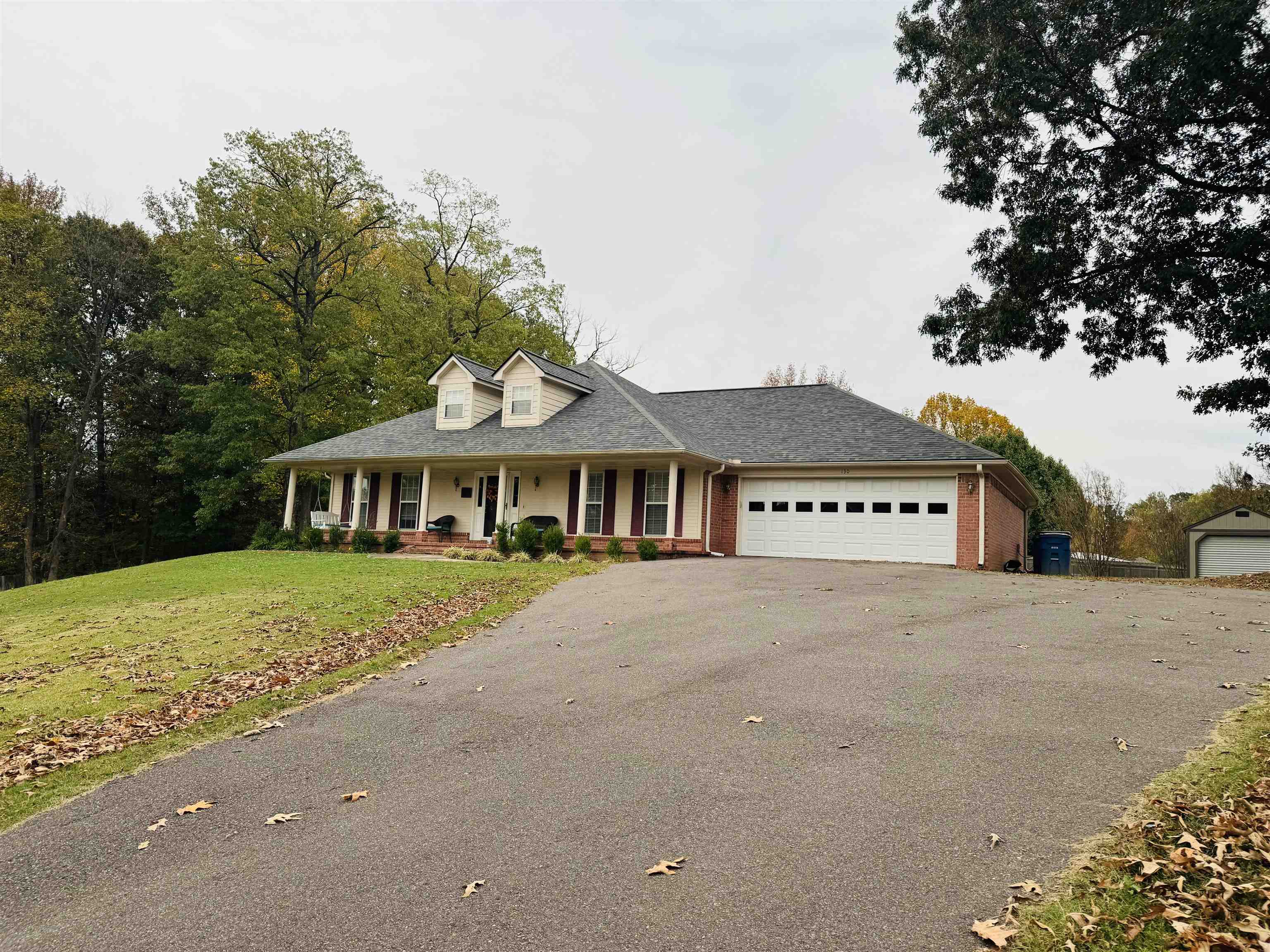 View of front of house featuring covered porch, a front yard, and a garage