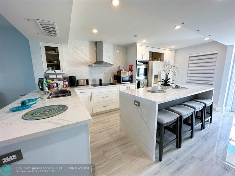 a kitchen with kitchen island stainless steel appliances a sink a stove a table and chairs