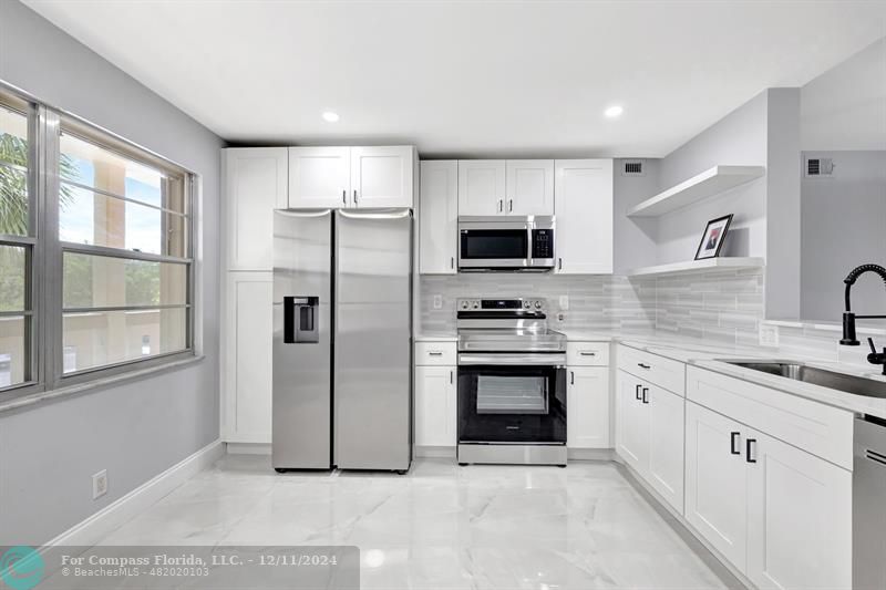 a kitchen with stainless steel appliances a refrigerator sink and microwave