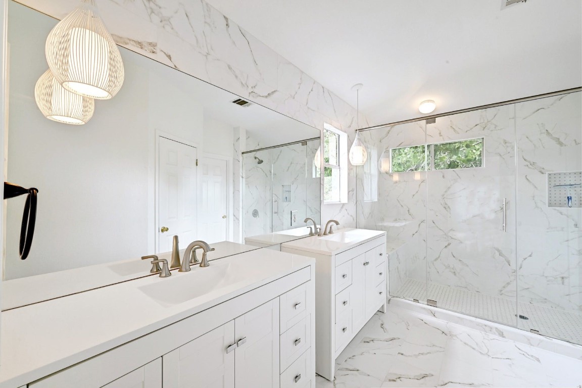 a bathroom with a double vanity sink mirror and shower