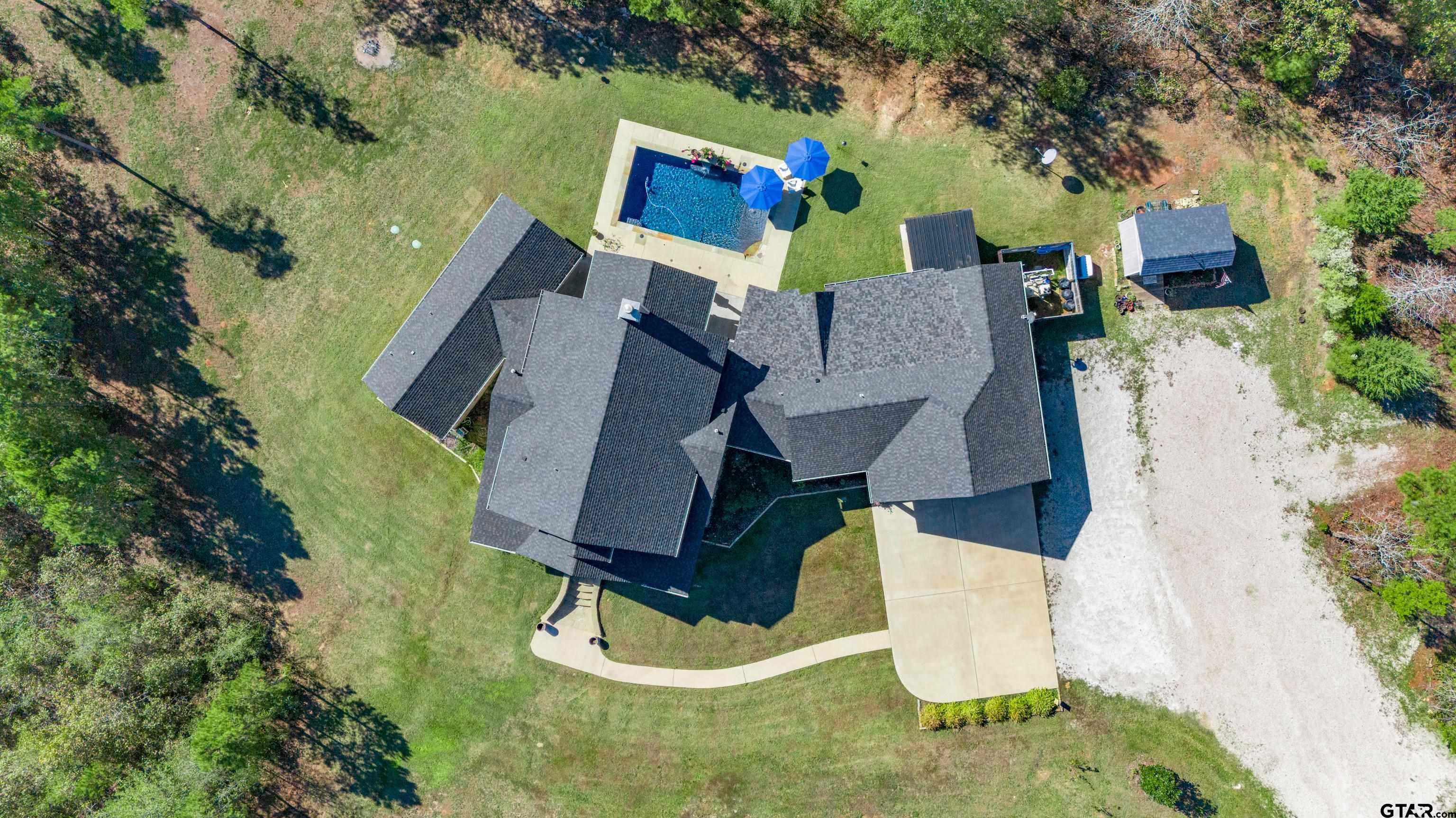 an aerial view of a house with swimming pool and large trees