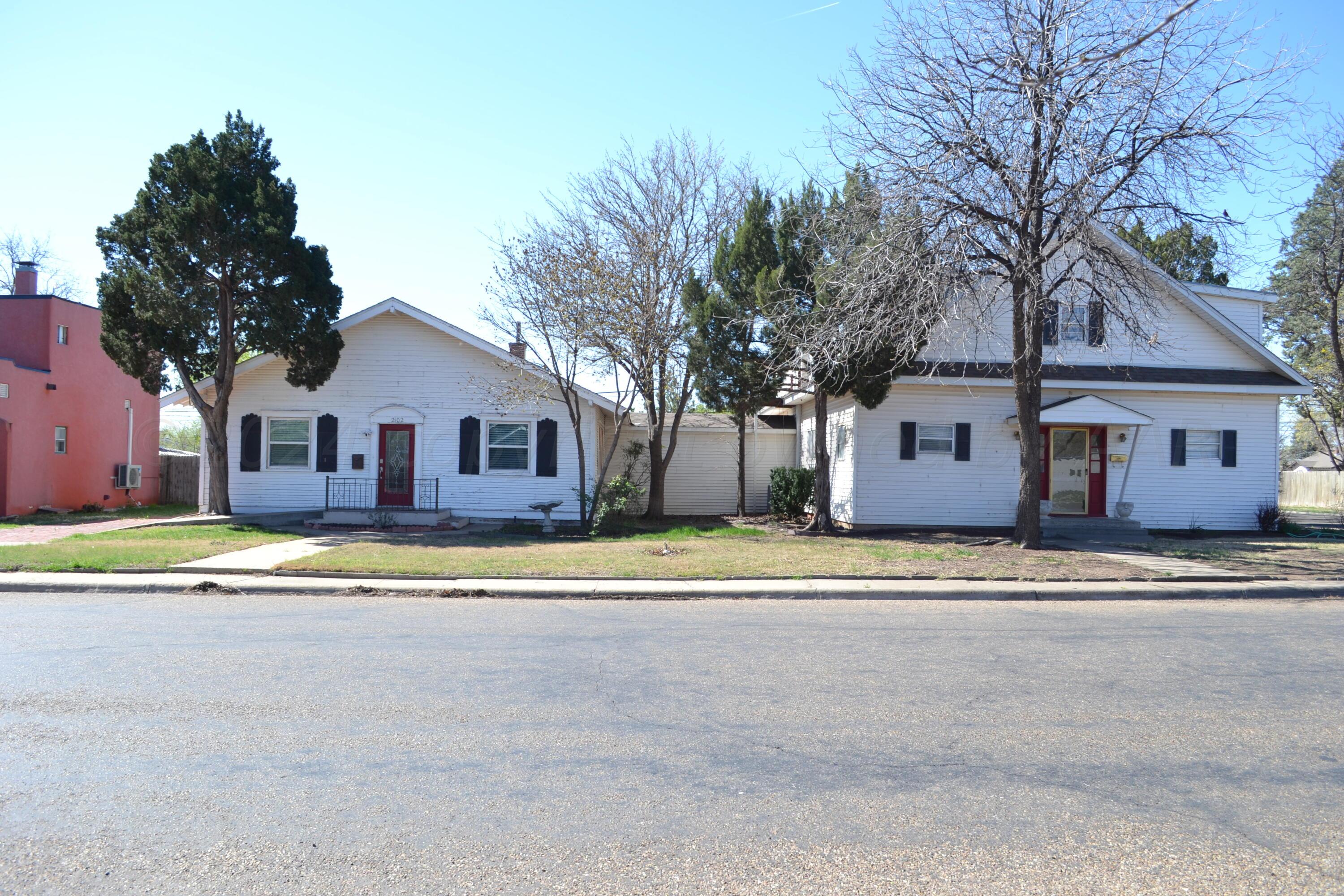 a view of a house with a yard and large trees