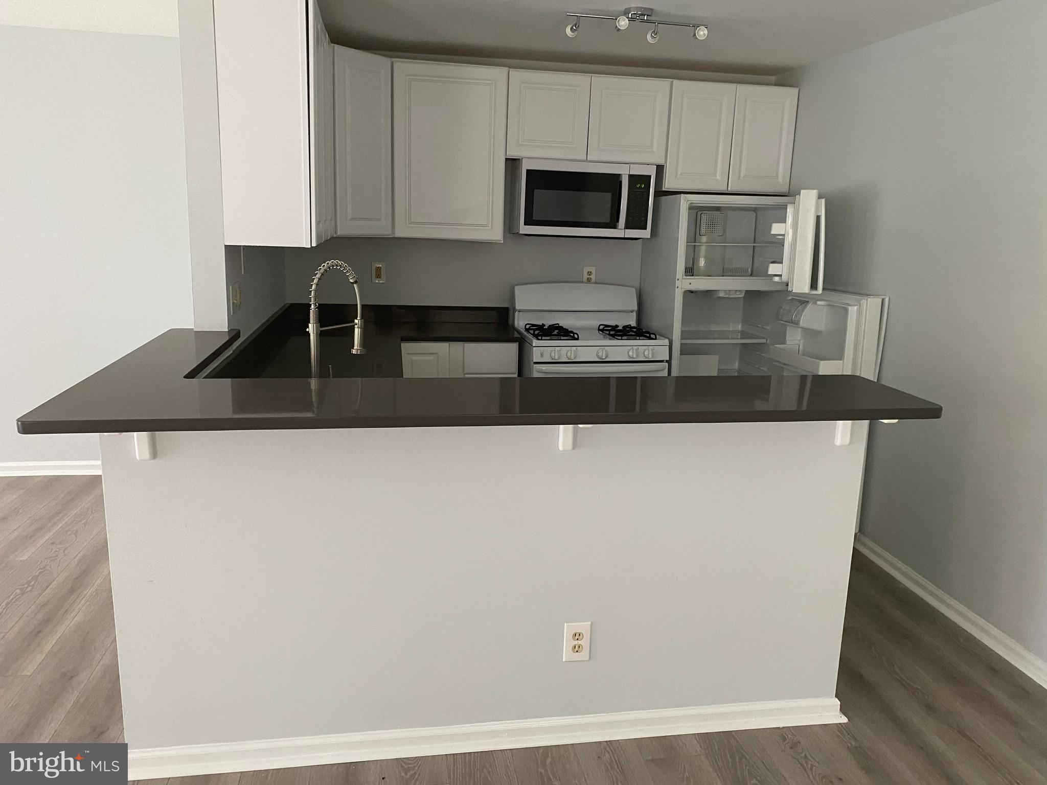 a kitchen with kitchen island a sink a microwave a stove and white cabinets