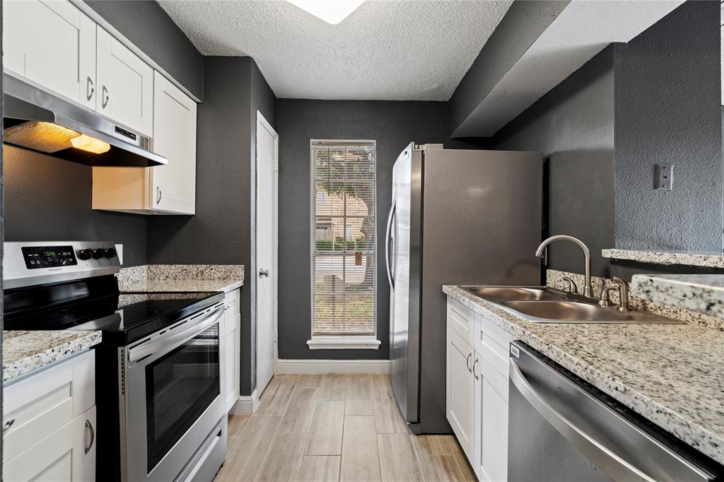 a kitchen with granite countertop a sink stainless steel appliances and cabinets