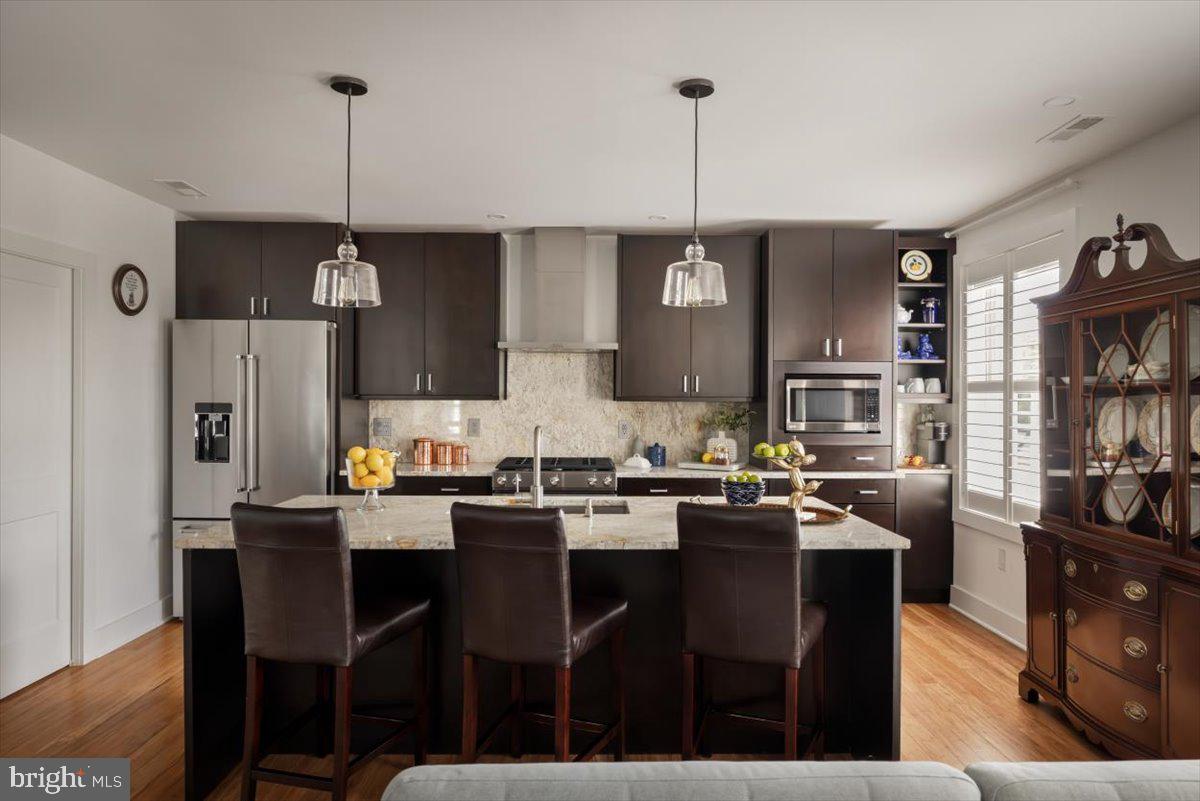 a kitchen with stainless steel appliances a dining table chairs and a wooden floor