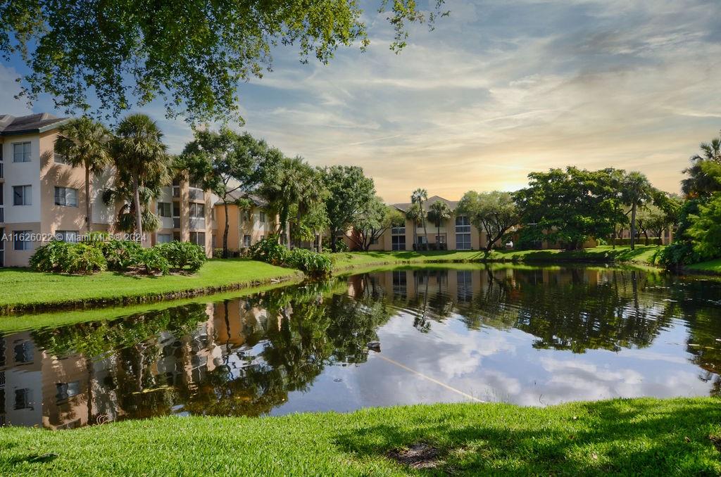 a view of a lake with a yard and large trees