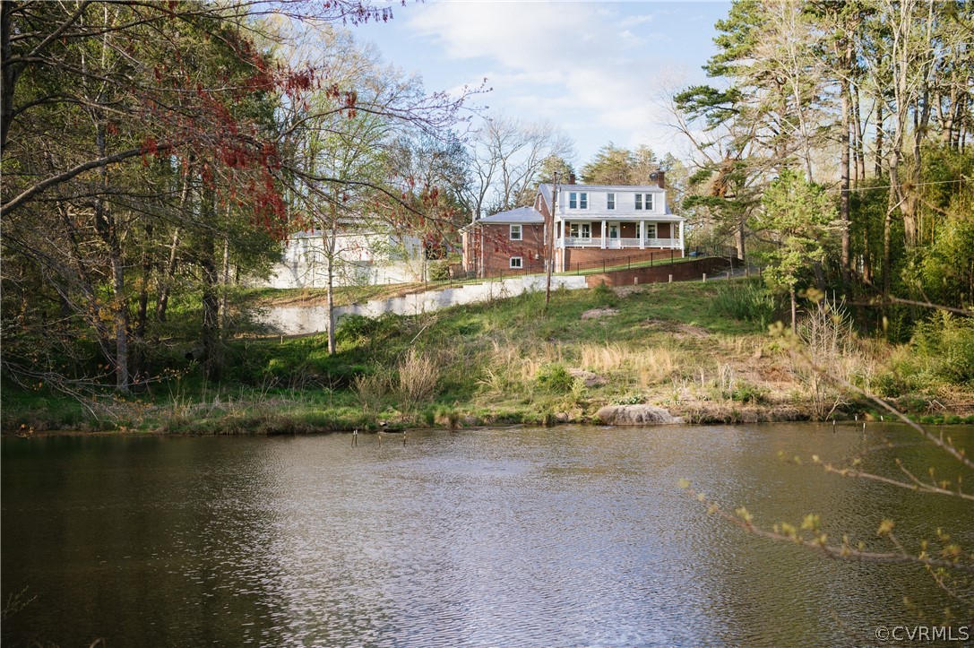 a view of a lake with a yard and large trees