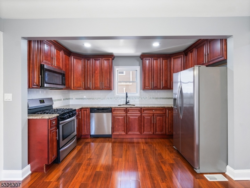 a kitchen with stainless steel appliances granite countertop wooden cabinets a stove top oven a sink and dishwasher