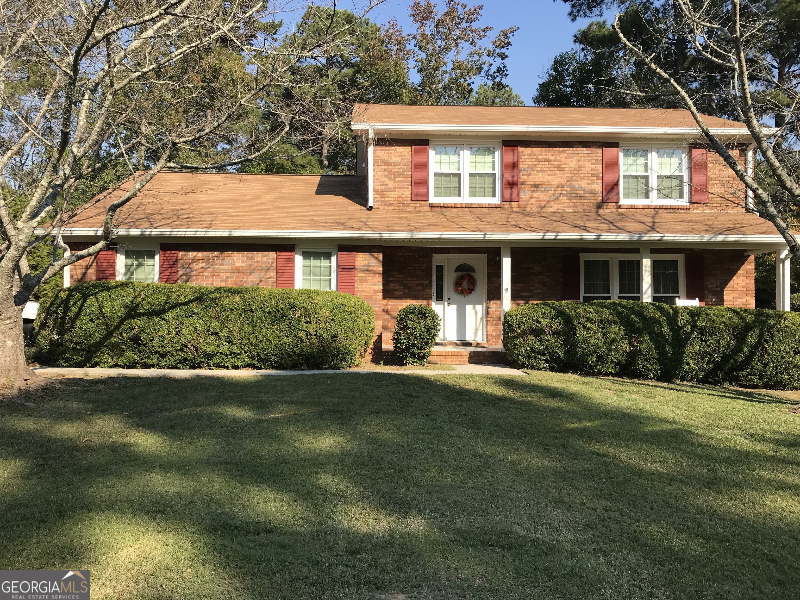 a front view of a house with a yard and trees