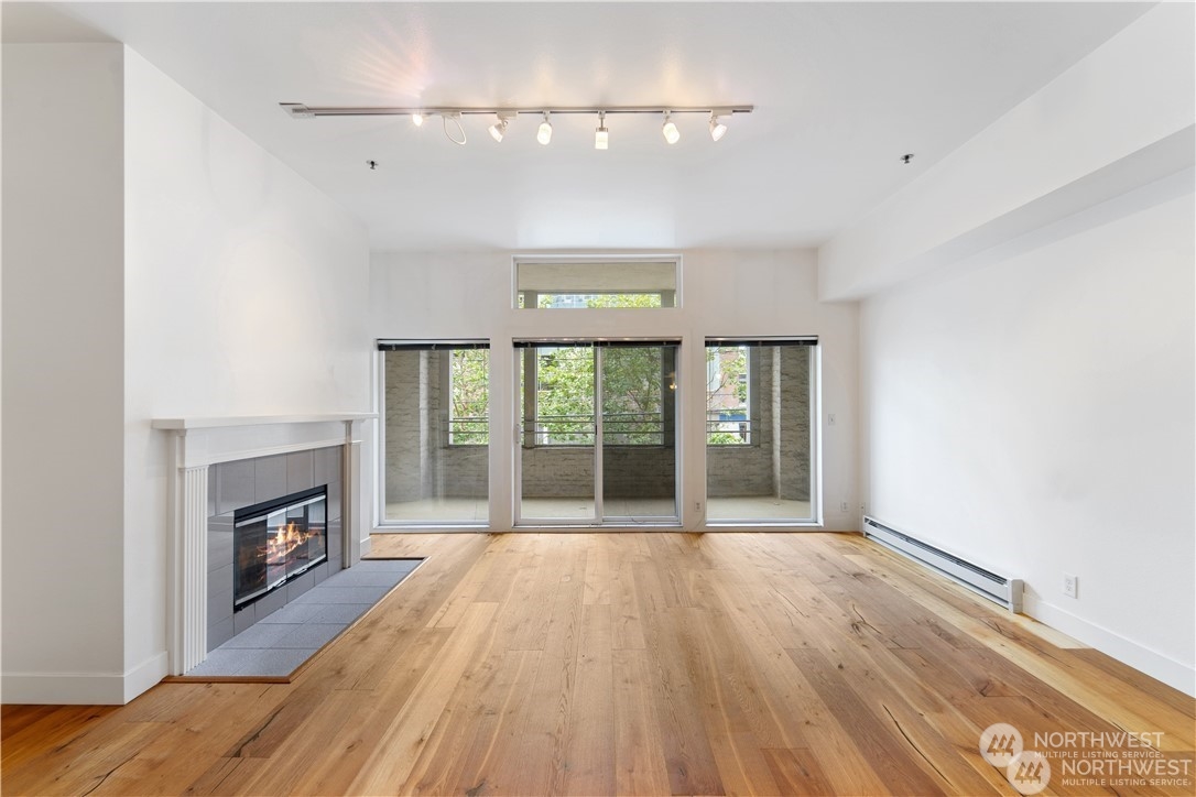 a view of an empty room with wooden floor fireplace and a window