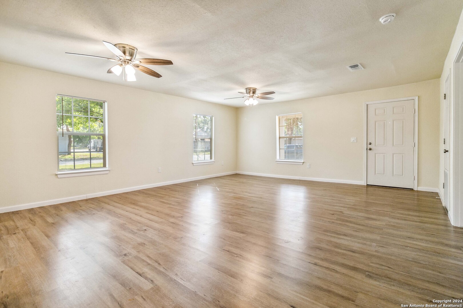 a view of an empty room with wooden floor and a window