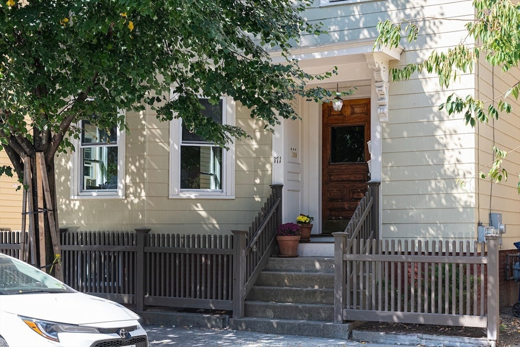 a view of a brick house with large trees and wooden fence