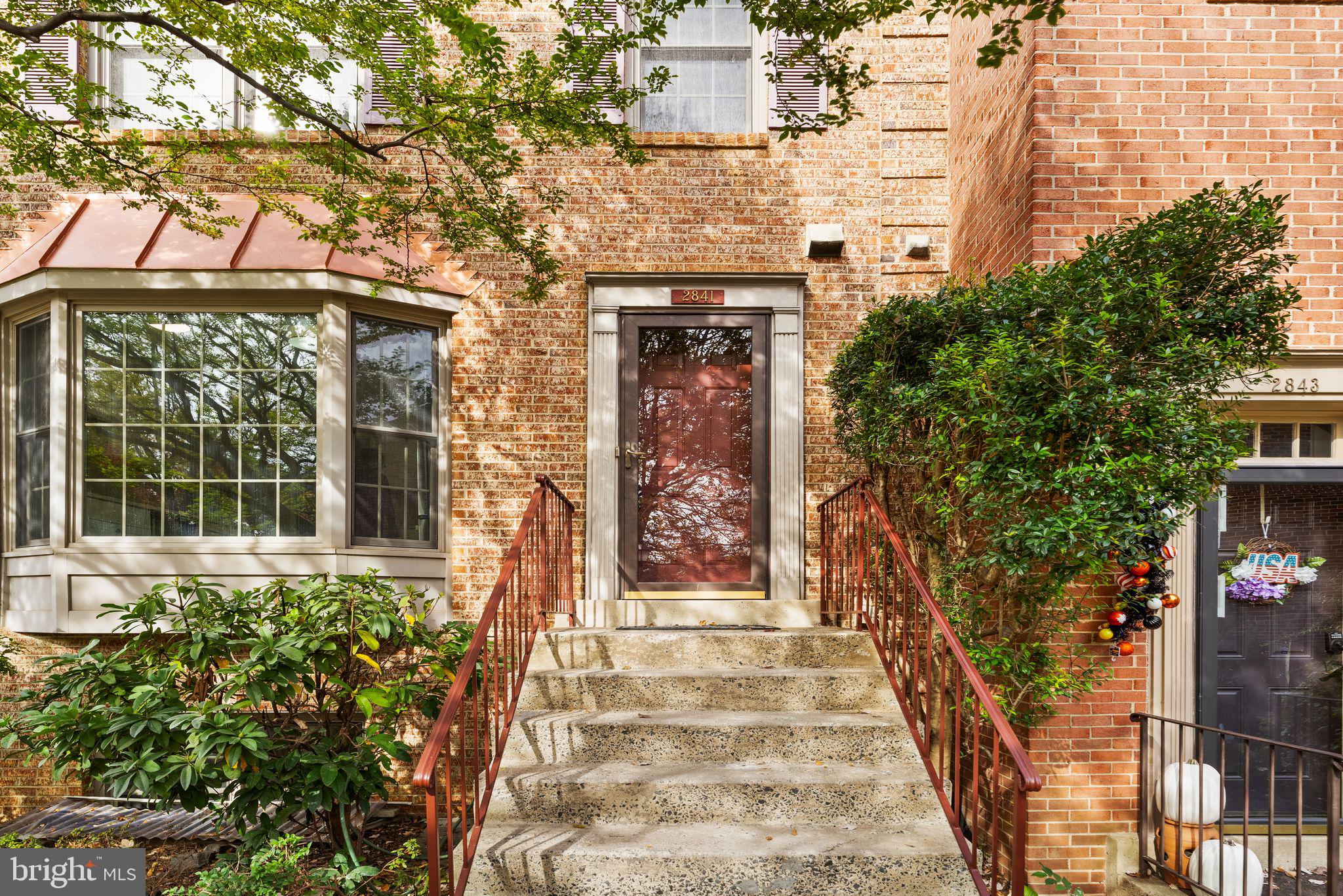 front view of a brick house with a large tree