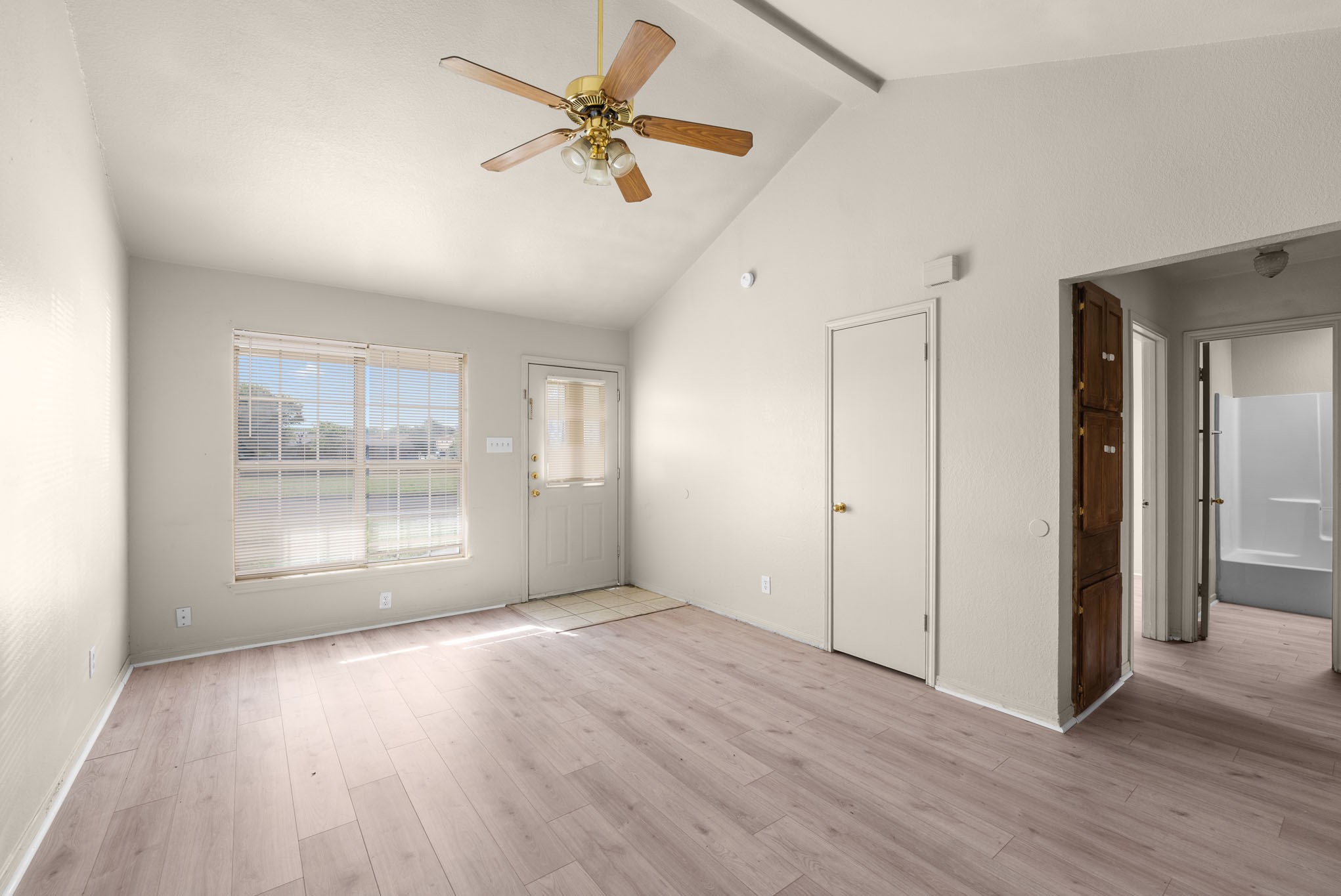 a view of an empty room with a window and wooden floor