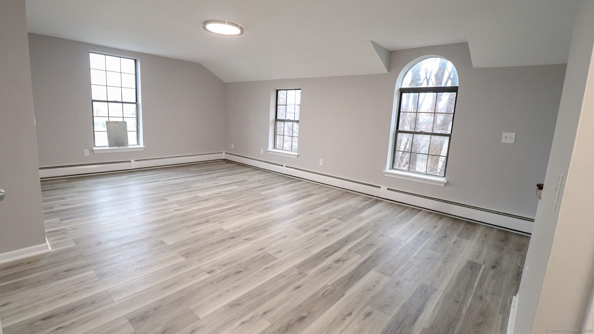 an empty room with wooden floor and windows