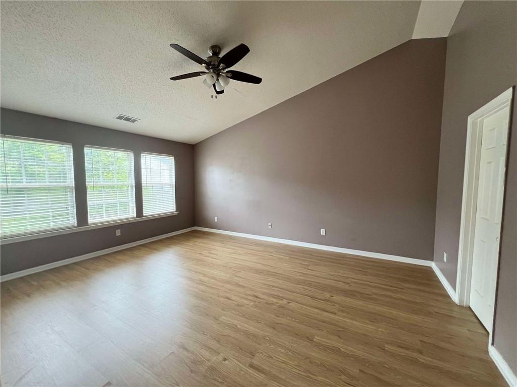 an empty room with wooden floor fan and windows