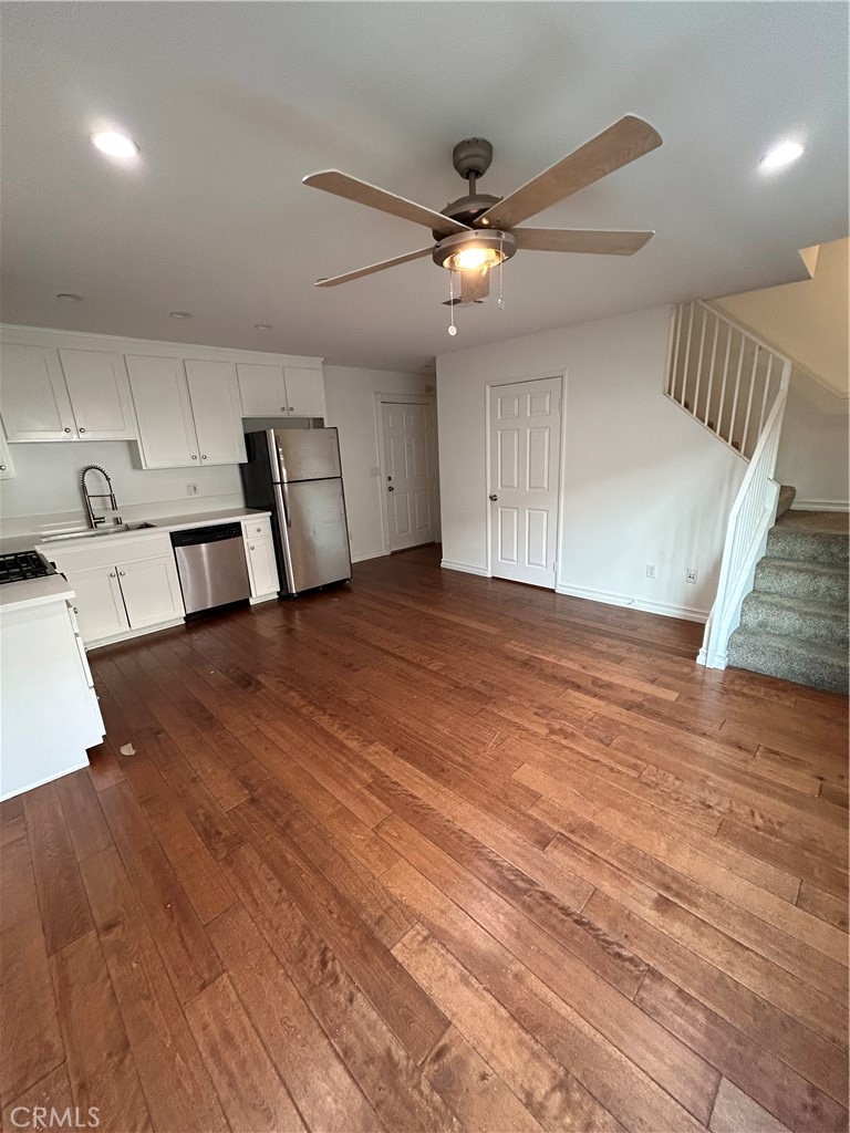 a view of an empty room with wooden floor and a ceiling fan