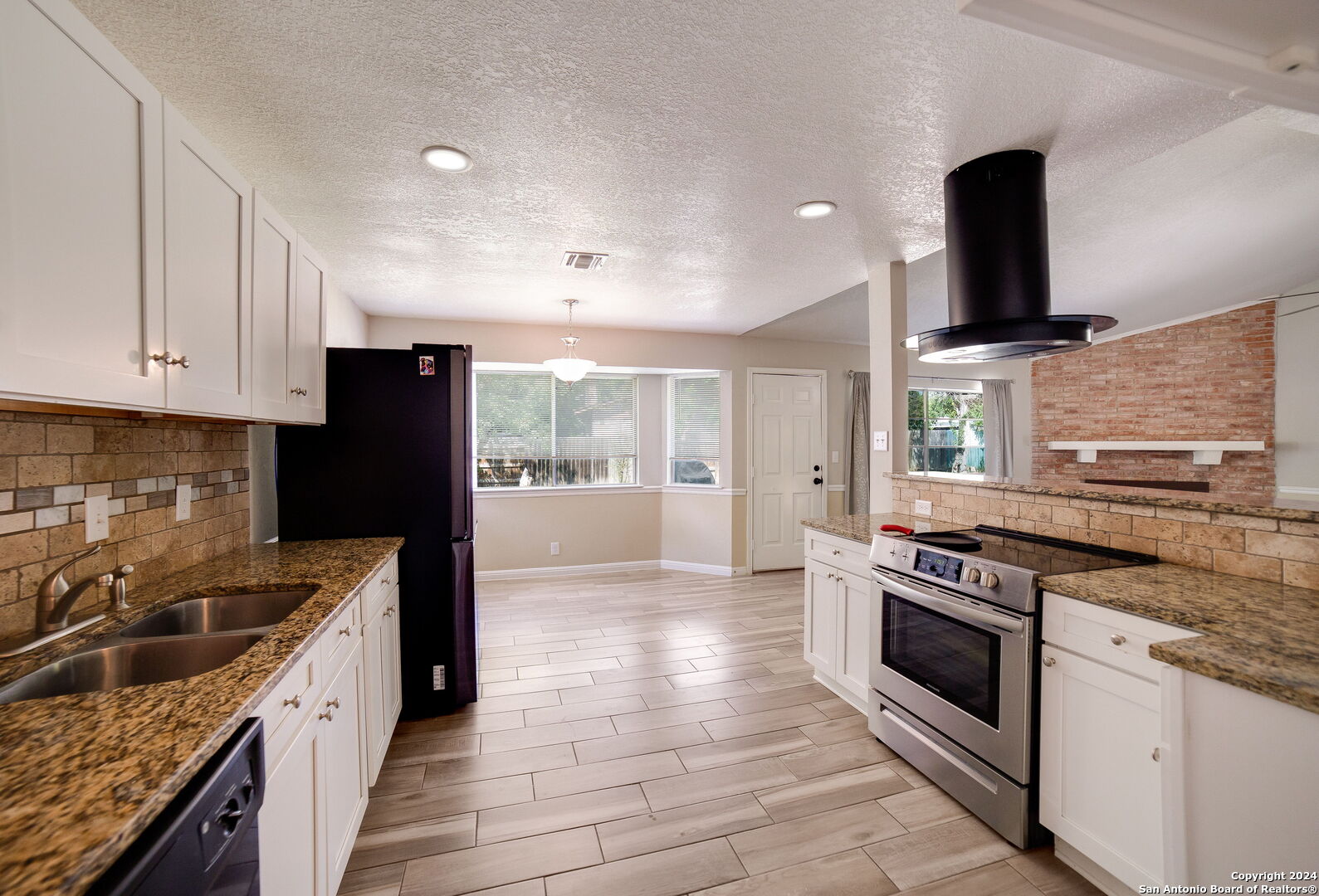 a kitchen with stainless steel appliances granite countertop a stove a sink and a refrigerator