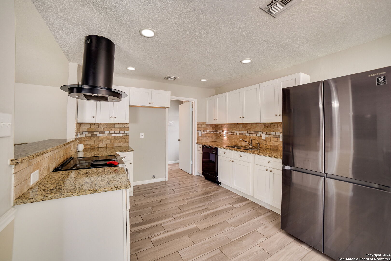 a kitchen with granite countertop a refrigerator stove top oven and sink