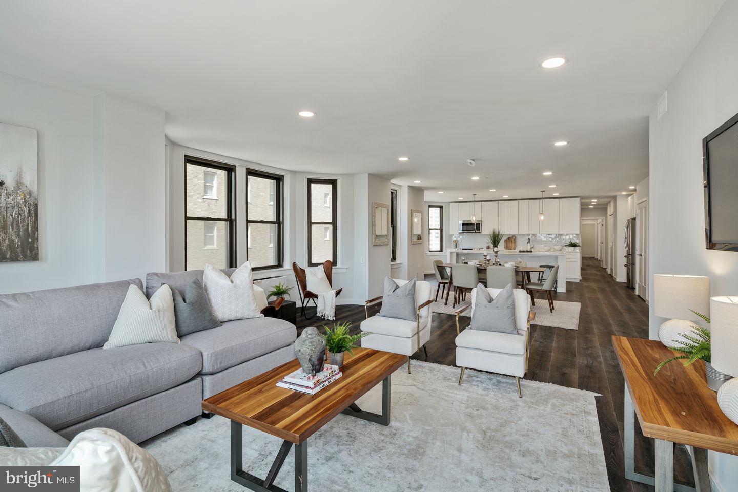 a living room with furniture kitchen view and a large window