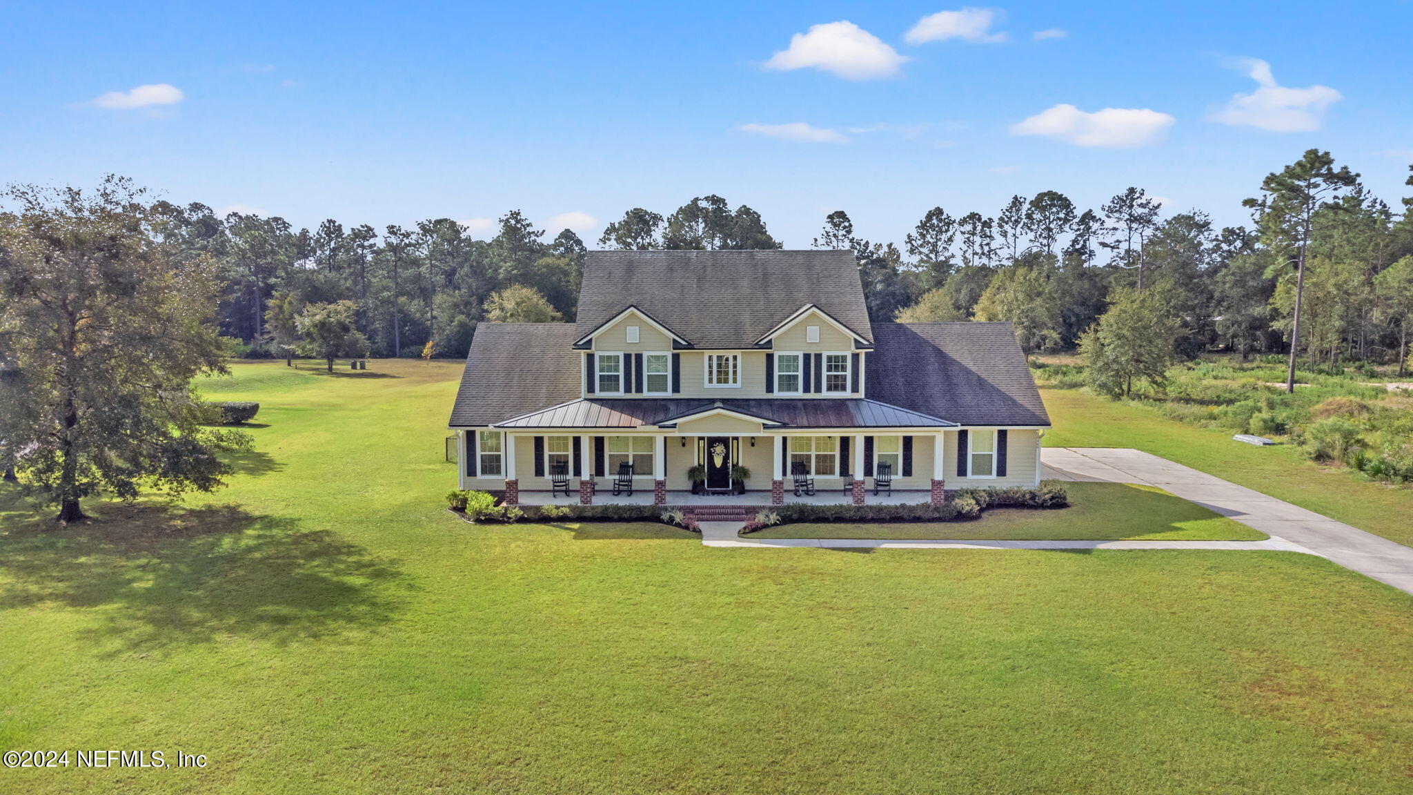 an aerial view of a house with swimming pool big yard and large trees