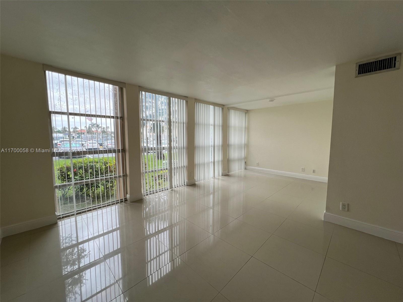 a view of an empty room with wooden floor and windows