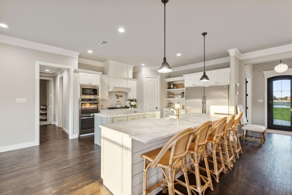 a room with stainless steel appliances kitchen island granite countertop a table chairs and a view of living room