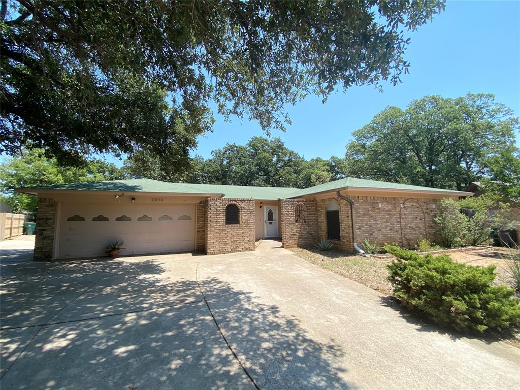 a backyard of a house with large trees and plants