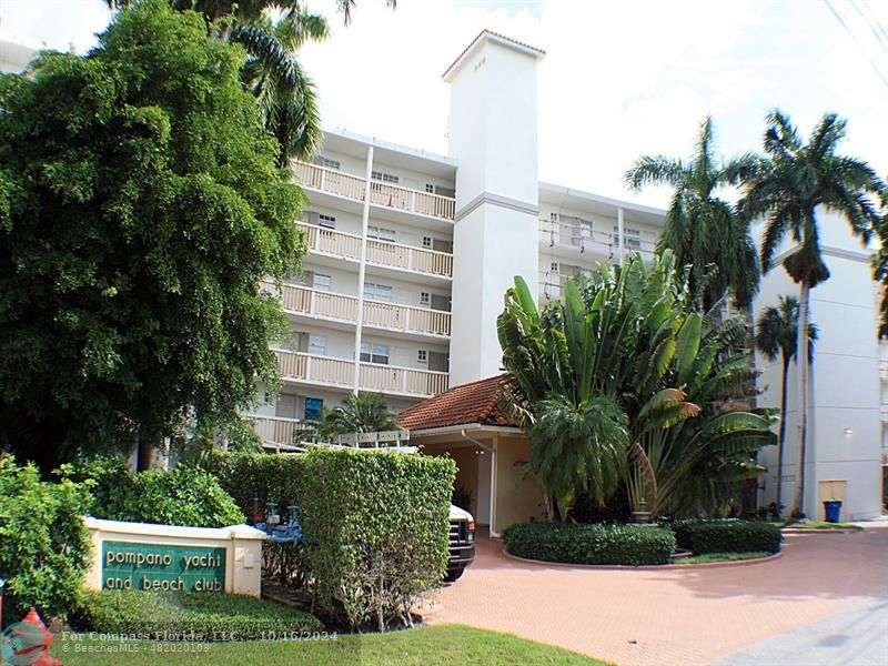 a front view of multi story residential apartment building with yard and green space