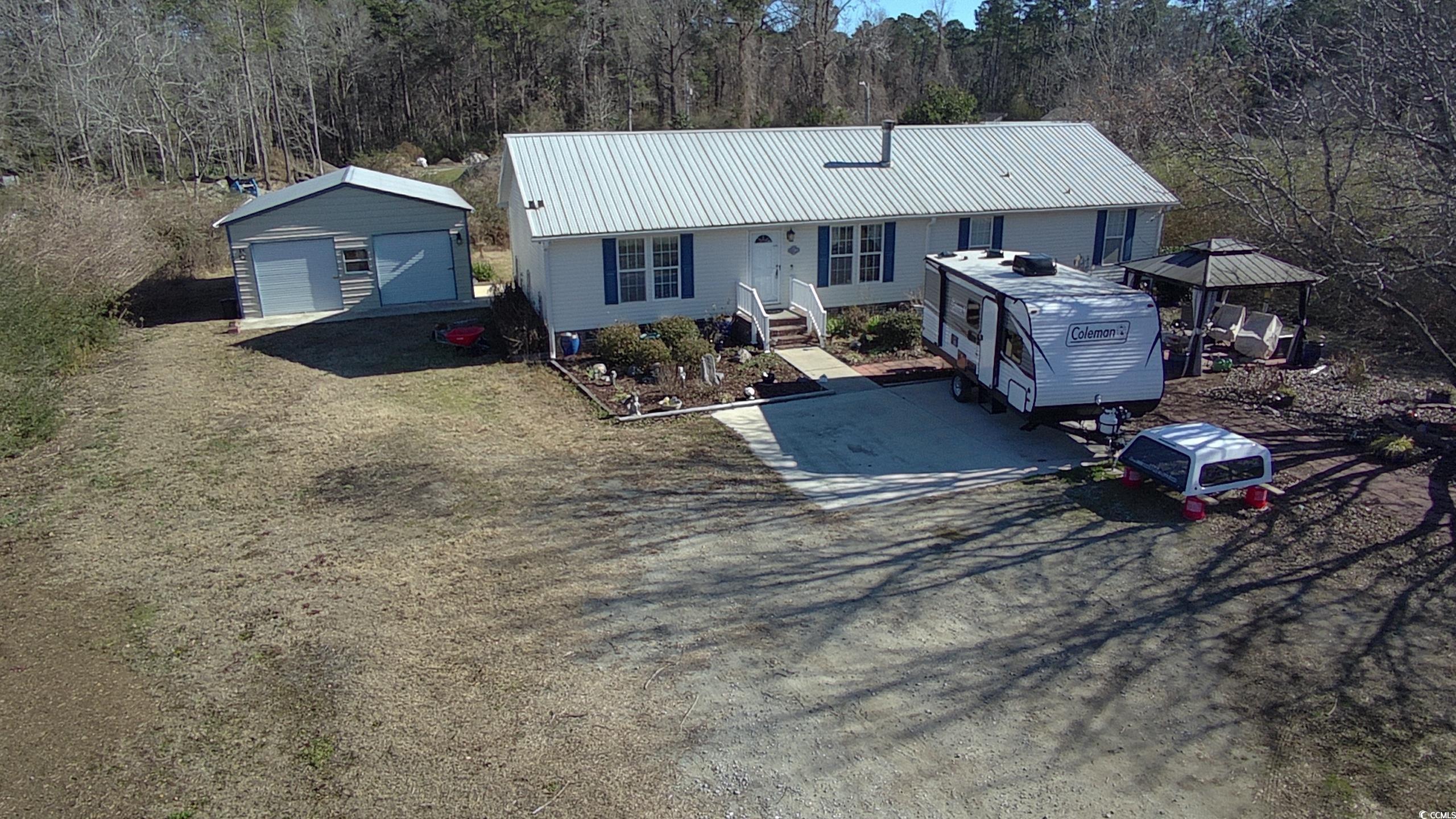 View of front of home with a garage and an outbuil