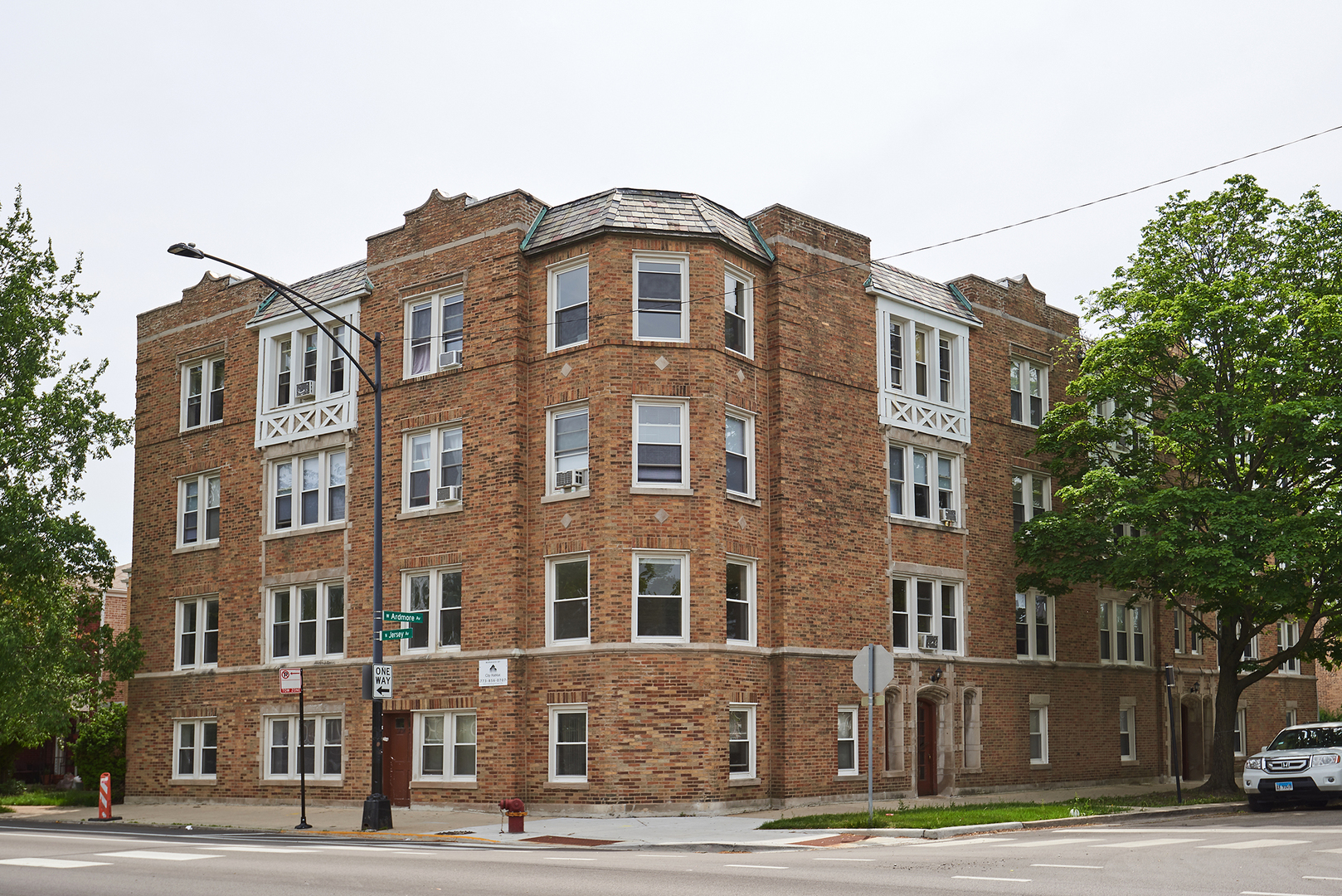 a front view of a building with lot of trees