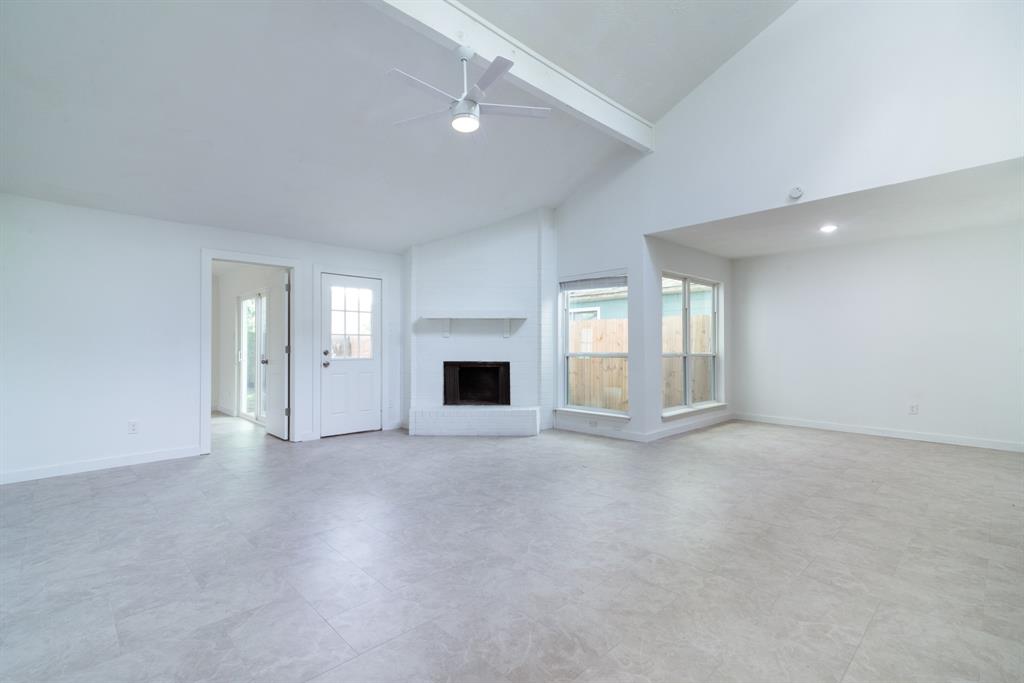 an empty room with windows and fireplace