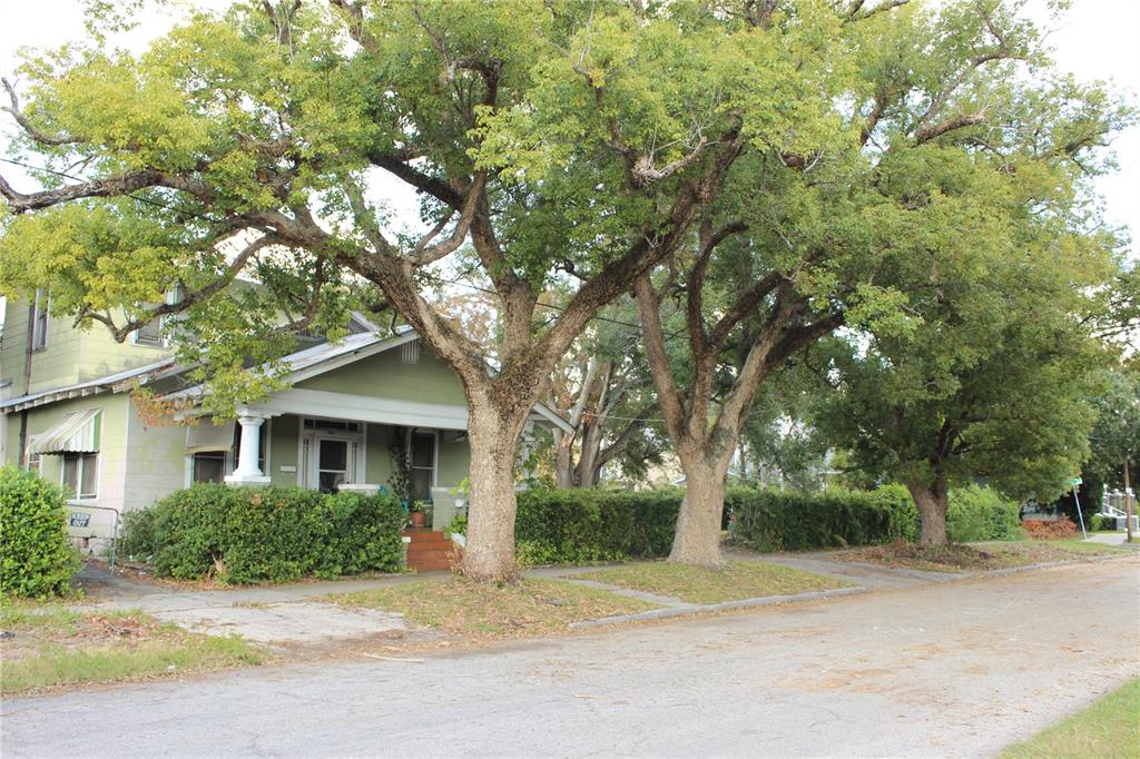 a front view of a house with a garden and tree