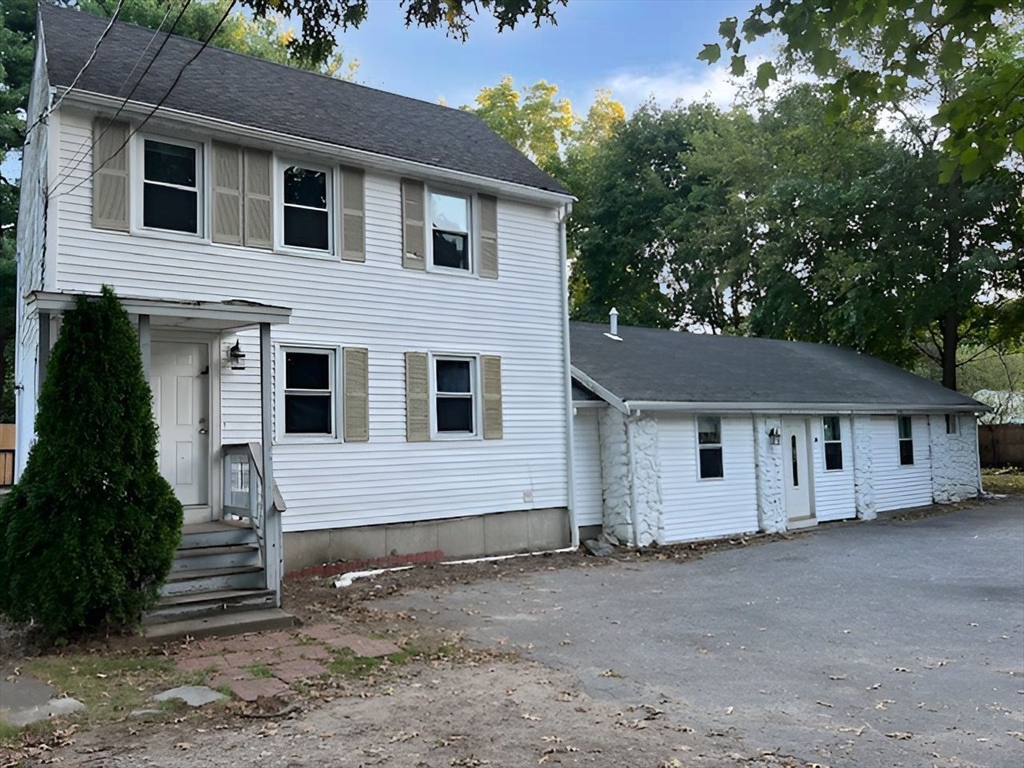 a view of house with a yard and large tree