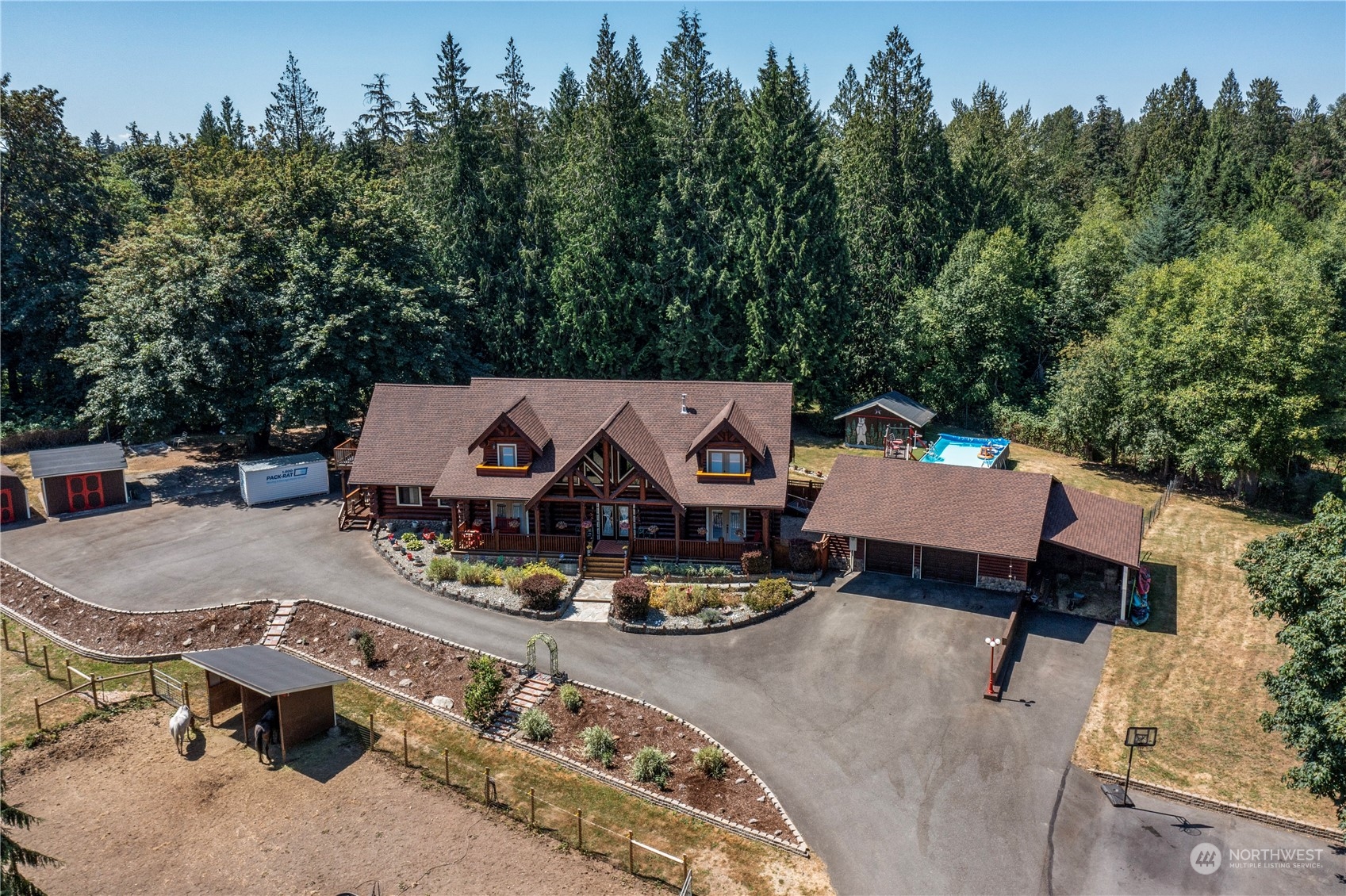 an aerial view of a house with swimming pool and trees in the background