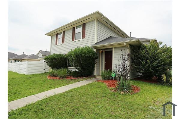 a front view of a house with a yard and potted plants