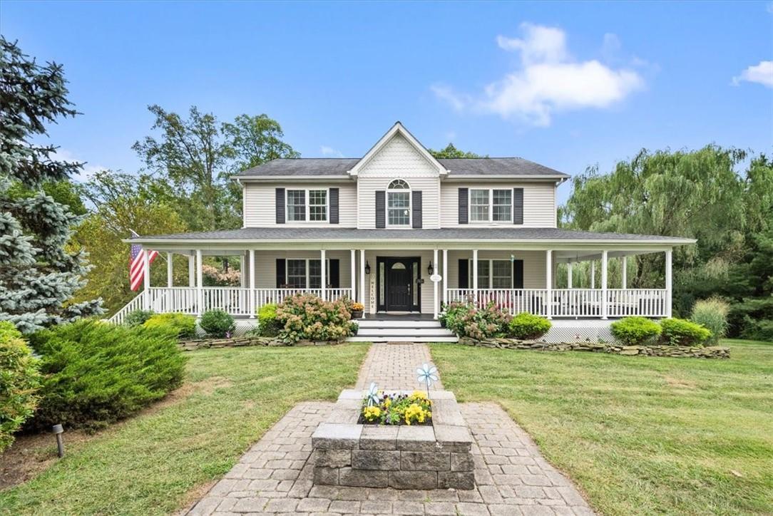 View of front of property with covered porch and a front yard