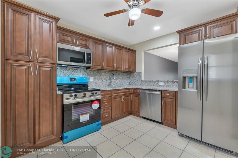 a kitchen with stainless steel appliances granite countertop a refrigerator sink and stove