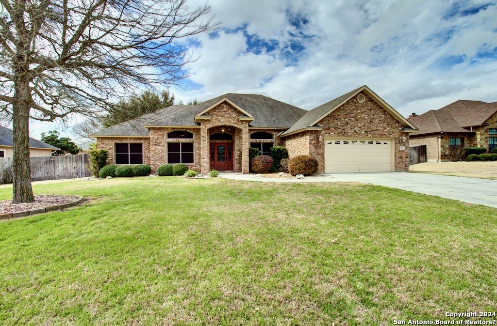 a front view of a house with a big yard and large trees